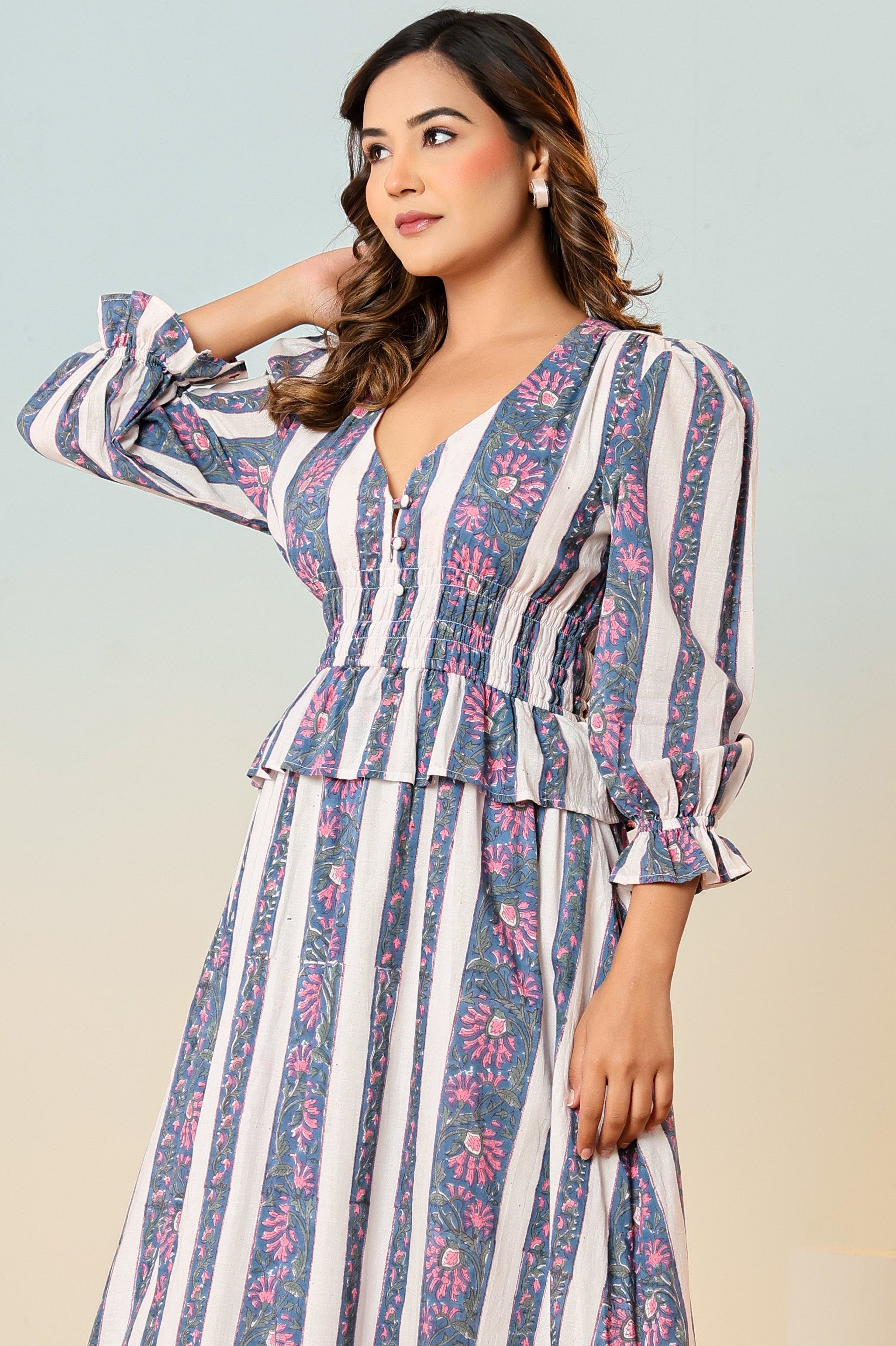 Woman wearing a striped dress with floral patterns on a neutral background