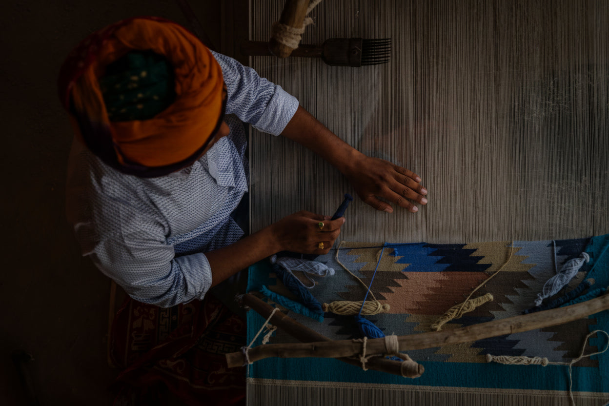 Person weaving a colorful pattern on a loom